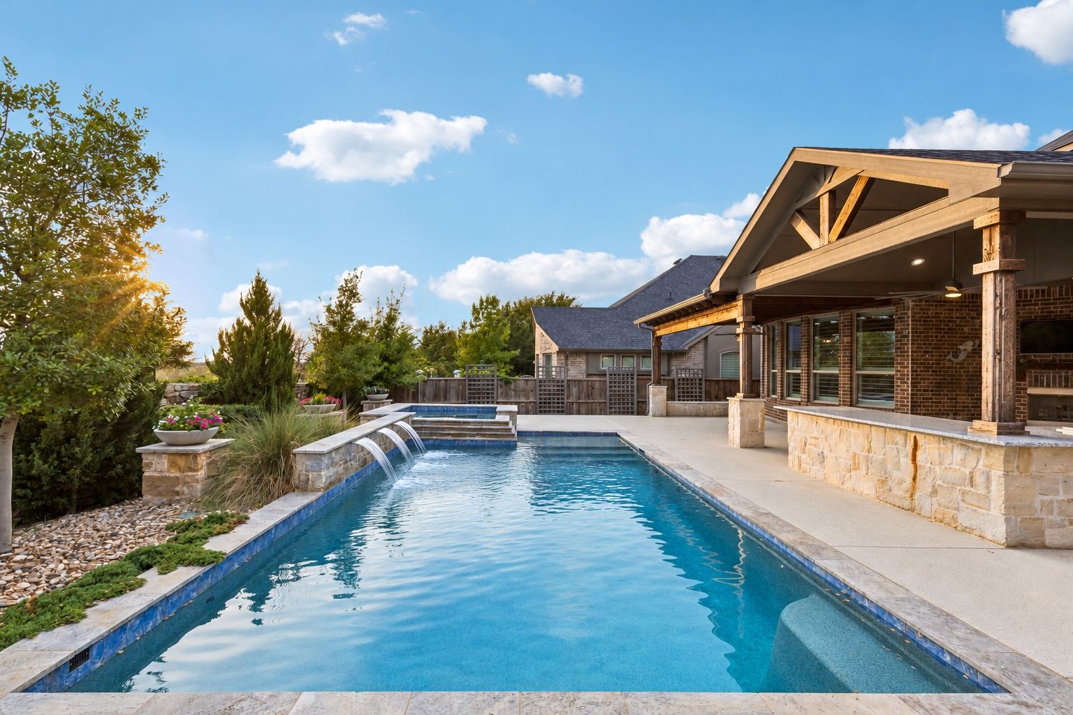 Heated saltwater pool & spa with sheer-descent water features is framed by the vaulted outdoor living area, oversized granite bar and mature landscaping
