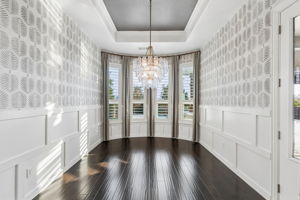 The dedicated dining room makes a statement with board-and-batten wainscoting, Serena & Lily wallpaper, custom drapery and a three-tier glass petal chandelier