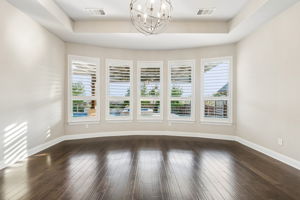 A bowed wall of plantation-shuttered windows fills the primary suite with natural light while capturing views toward the backyard and pool.