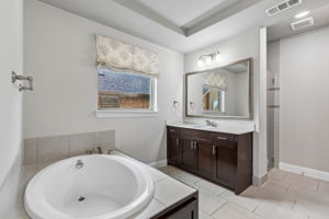 Dual vanities & garden tub, creating generous space within the primary bath. Window does have light filtering roller shade under the roman shade.