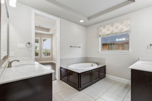 Dual vanities & garden tub, creating generous space within the primary bath. Window does have light filtering roller shade under the roman shade.