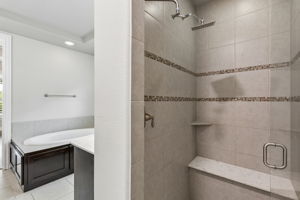 The primary bath features a spacious walk-in tiled shower with bench seating and frameless glass.
