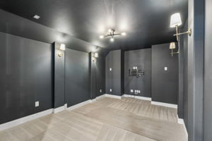 he dedicated pre-wired media room is finished in deep charcoal with updated gold sconces and statement ceiling lighting for a polished, theater-inspired atmosphere.
