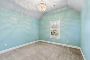Vaulted ceilings, plantation shutters and a designer light fixture add character to this upstairs secondary bedroom.