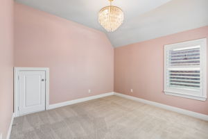 Vaulted ceilings, plantation shutters and a designer light fixture add character to this upstairs secondary bedroom.