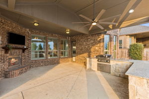 Designed for entertaining, the covered patio brings together a fireplace, TV and oversized granite pool bar with built-in grill beneath a dramatic vaulted ceiling.