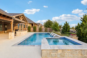 The heated saltwater pool and attached spa feature sheer-descent water elements and are surrounded by thoughtfully designed outdoor living spaces and mature landscaping