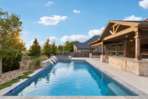 Heated saltwater pool & spa with sheer-descent water features is framed by the vaulted outdoor living area, oversized granite bar and mature landscaping