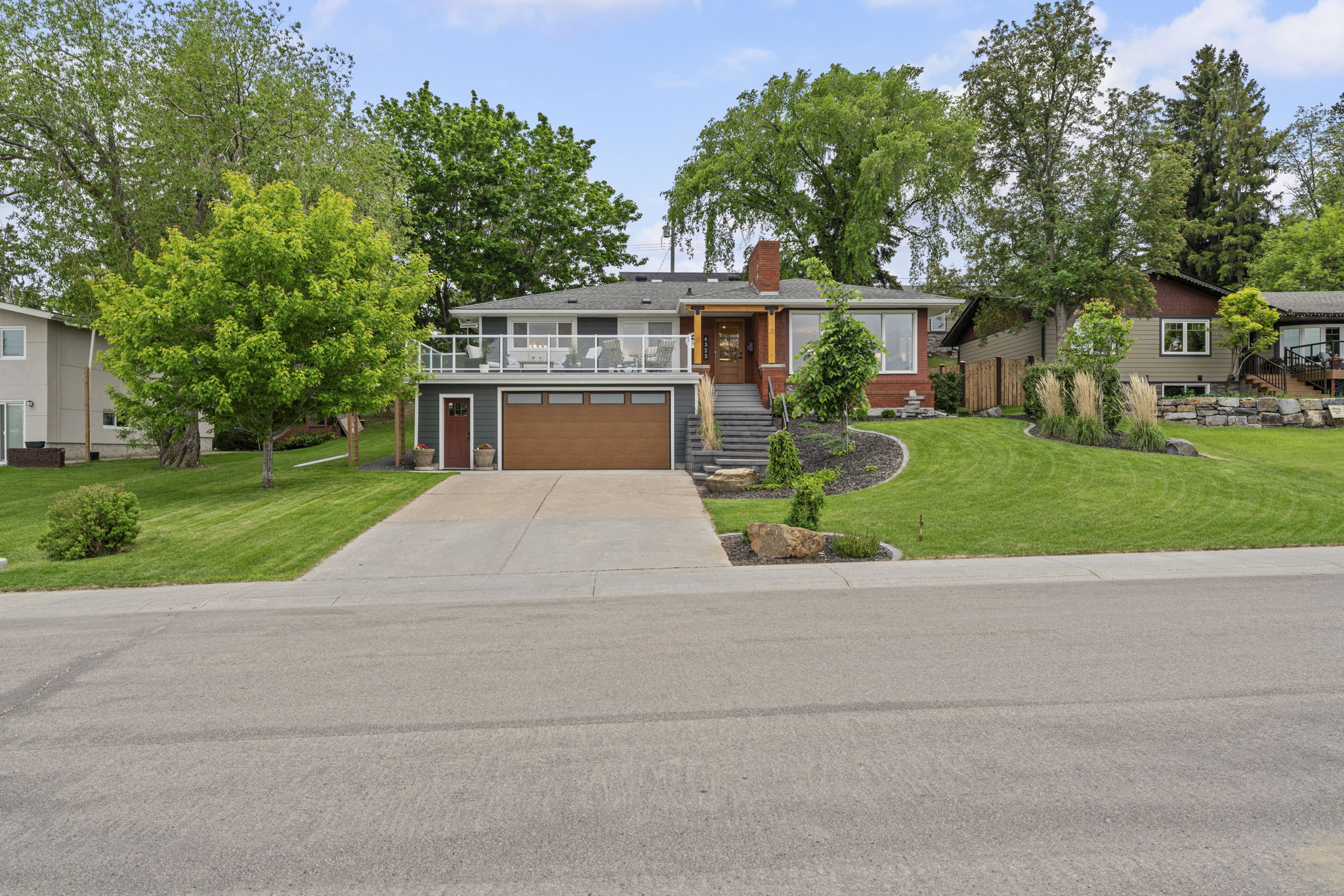 Front elevation of the Hardisty Drive home with a raised terrace, garage and lawn.