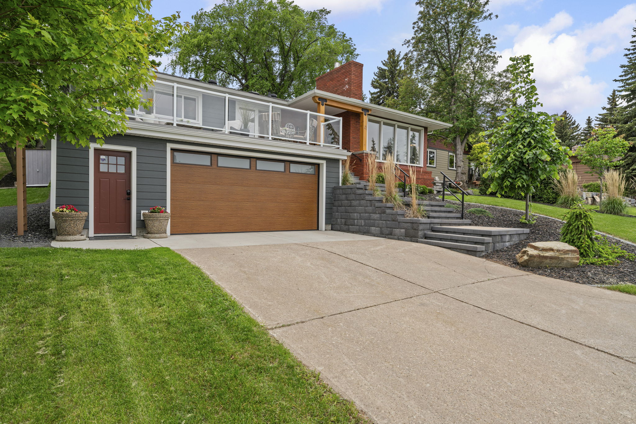 Driveway and attached garage beneath the home's glass-railed front terrace.