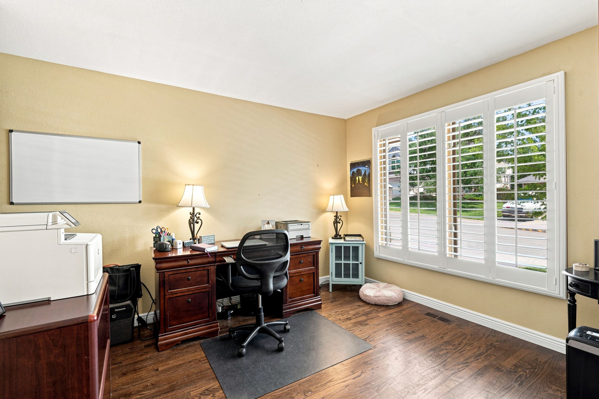 Private office includes french doors,  plantation shutters,  nook for shelving hardwood floors.