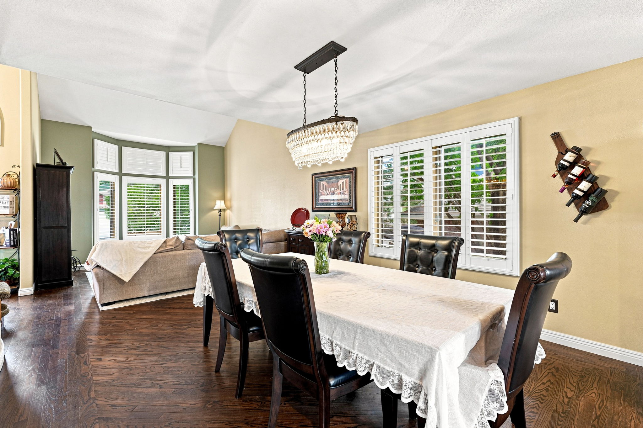 Dining room with updated lighting, plantation shutters, hardwood flooring.
