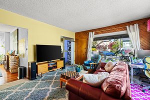 Main: Living room with large front window, large bedroom off living area