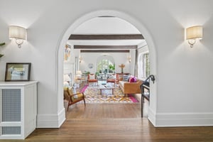 Stunning sunken living room invites relaxed conversation and merriment beneath exposed beams, with a wood-burning fireplace anchoring the space in charm.
