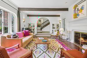 With windows on two sides, beamed ceilings above, and a wood-burning fireplace, this living room invites you to linger just a little longer.
