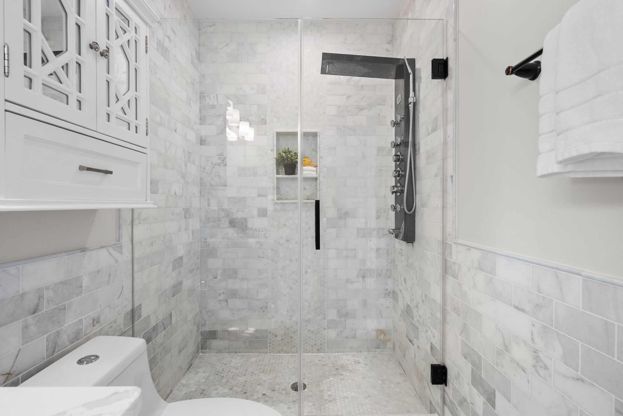 Walk-in shower with a glass enclosure and body jets