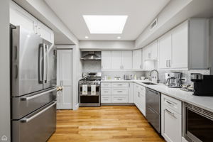 Beautifully appointed with custom cabinetry, quartz countertops, a large quartz breakfast bar and a skylight that creates an exceptionally bright and inviting space