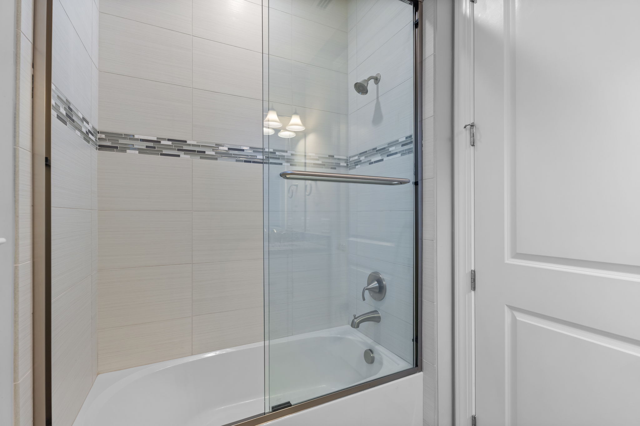 Second bathroom shower with glass enclosure and deorative title details