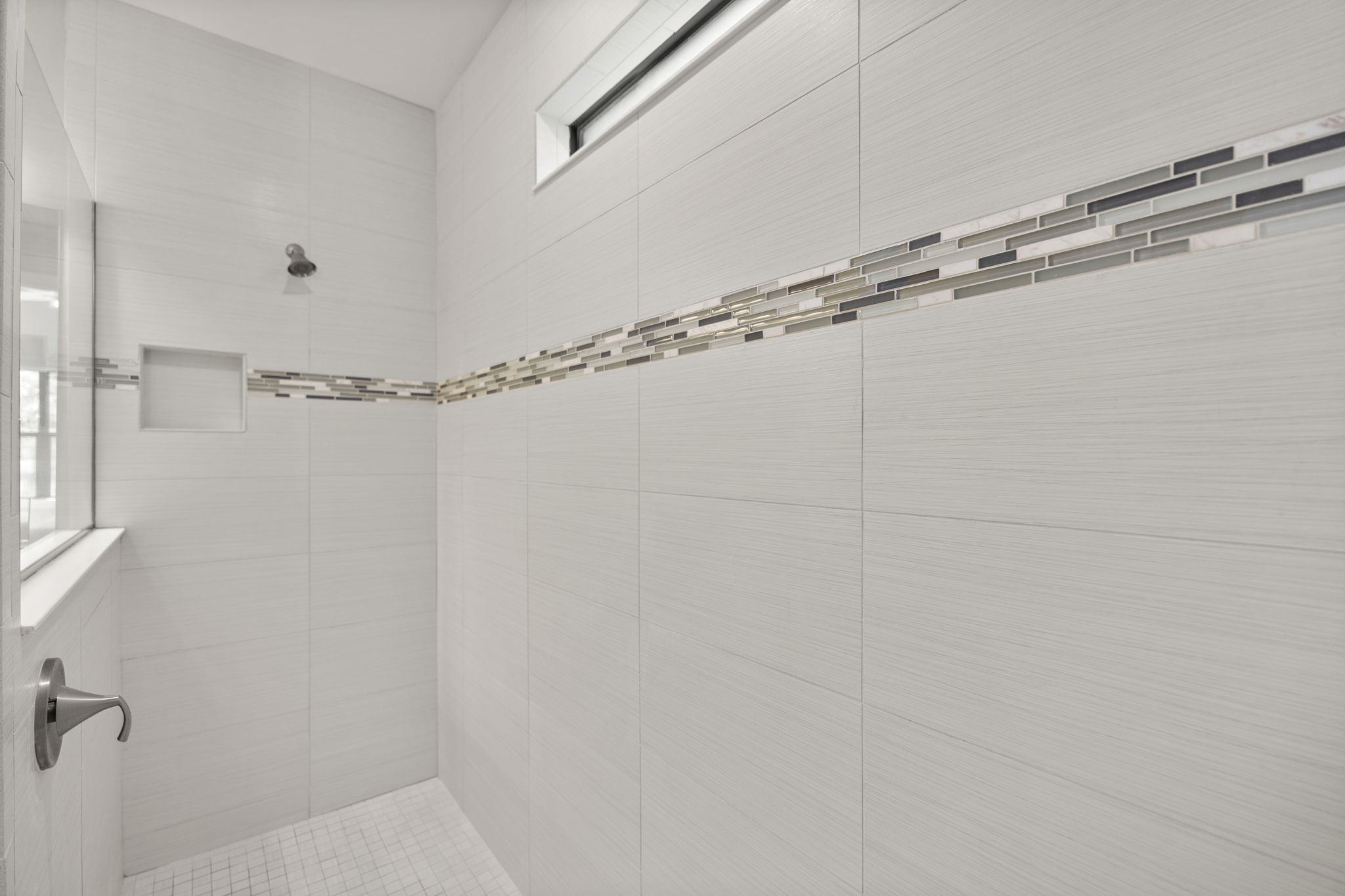 oversized walk in shower with decorative tile detail