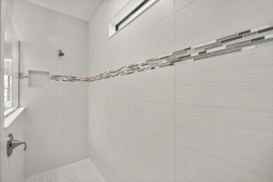 oversized walk in shower with decorative tile detail