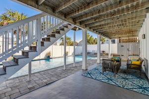 An open patio provides a shaded area for poolside lounging.