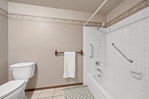 Guest bath with full tub and grab bars.