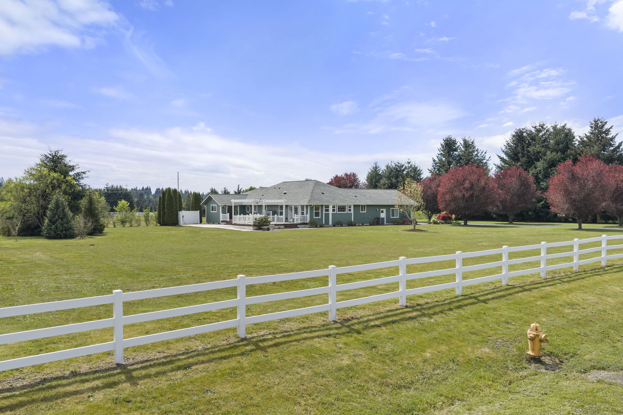 Charming white fence lines the front, creating a warm and inviting entrance