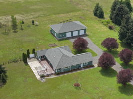 Large rambler home with a 2,400 sq ft shop with 10K lift, multiple oversized doors (3–10', 1–12'), and 3/4 bath with laundry
