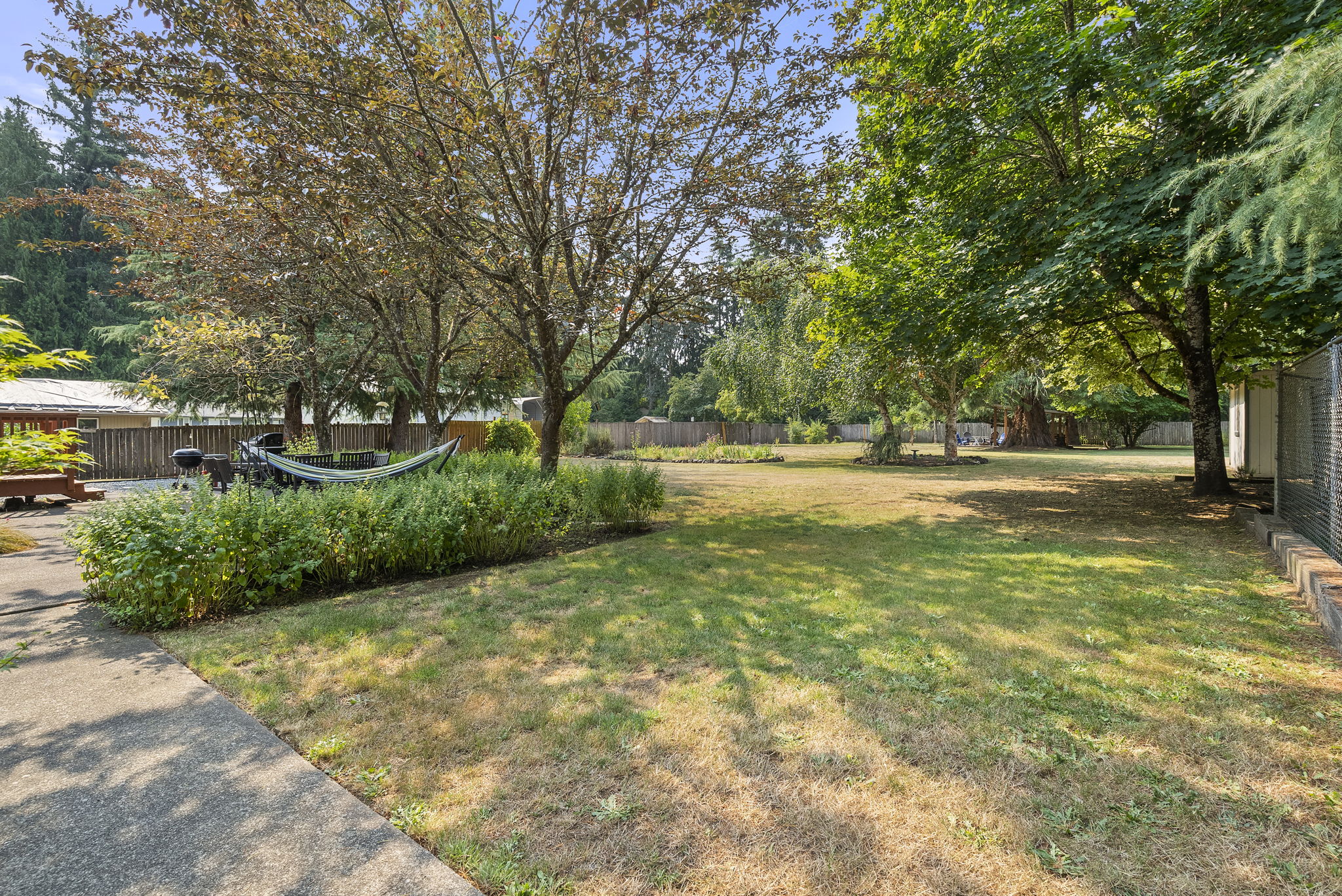 An expansive backyard with mature trees offers privacy, shade, and endless possibilities for recreation, gardening, or future additions.