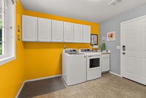 Spacious laundry room with utility sink, abundant cabinetry, and direct exterior access—perfect as a functional mudroom.