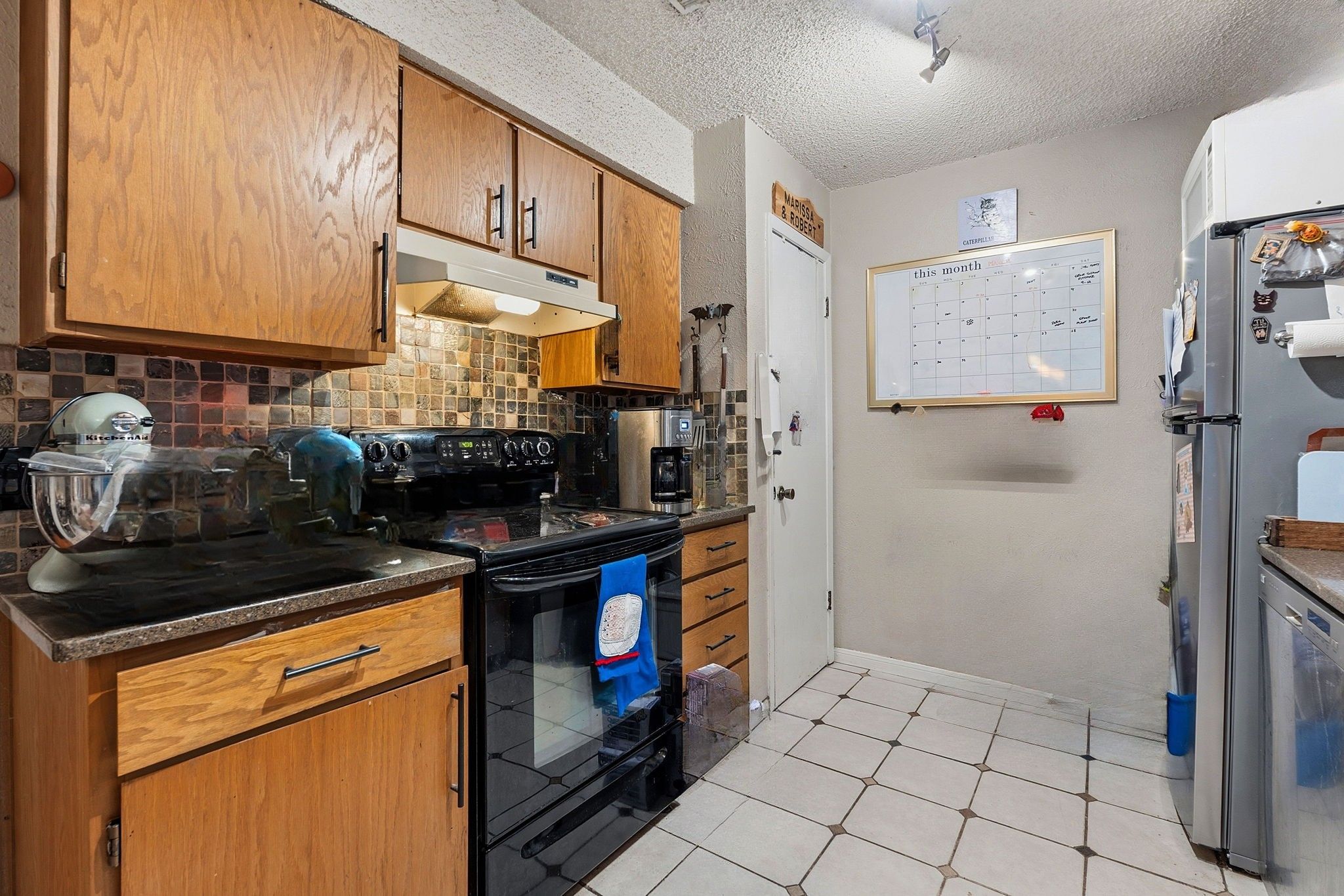 Unit B. Kitchen with updated counters, backsplash, tile floor.
