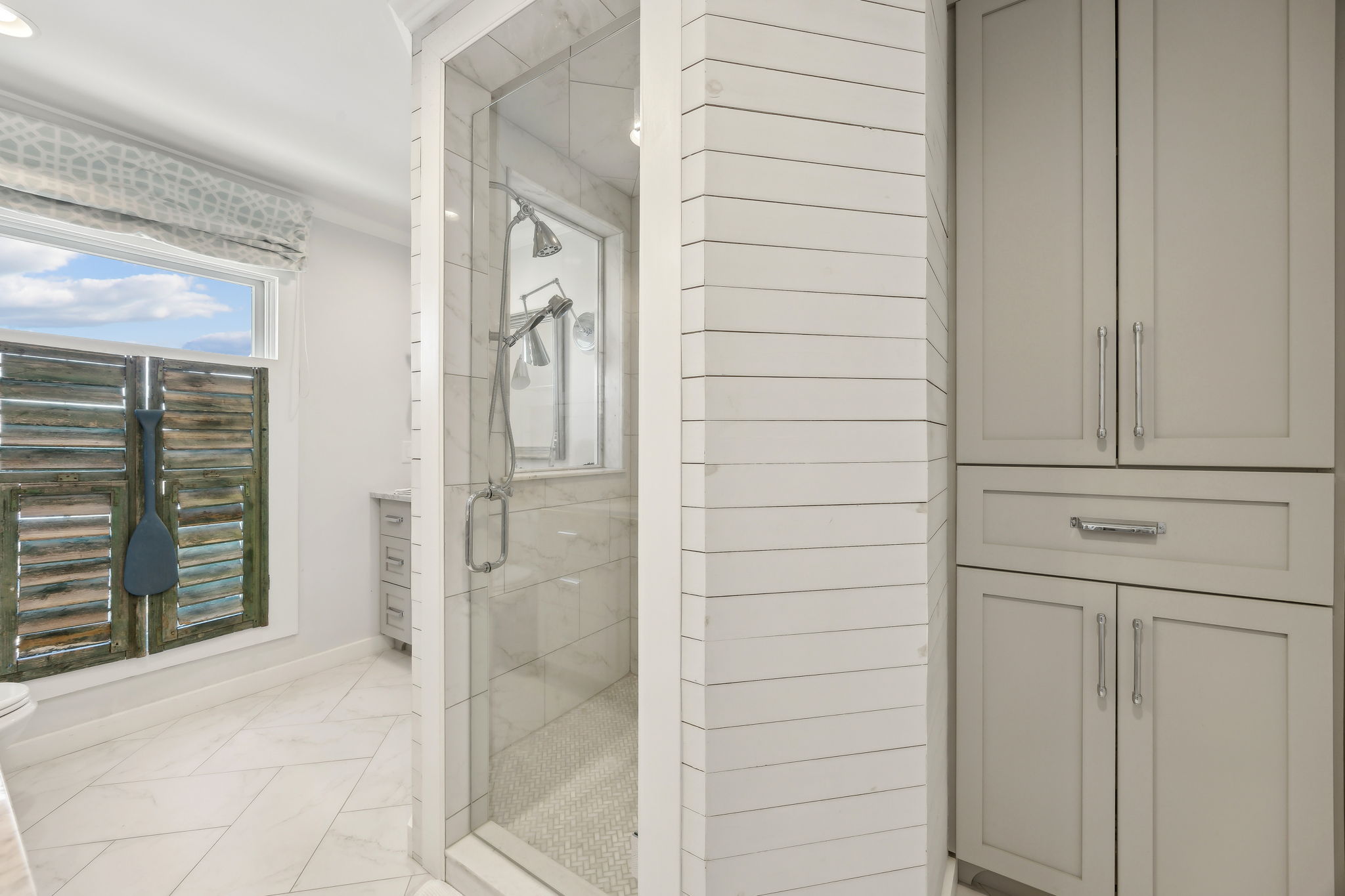 A glass-enclosed shower and built-in storage add everyday function to the suite’s refined style.