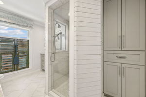 A glass-enclosed shower and built-in storage add everyday function to the suite’s refined style.