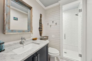 The guest bath feels fresh and polished, with shiplap detail, quartz counters, and a walk-in shower.