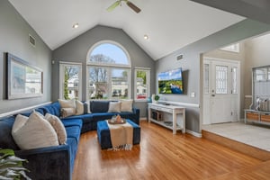 Living room with vaulted ceiling and arched window. Volume, light - a space that feels expansive yet incredibly comfortable.
