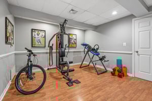 Lower level interior room used as a gym with attached utility closet.