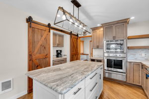 Double pantry storage behind the sliding barn doors. Wall oven, built in microwave and warming drawer