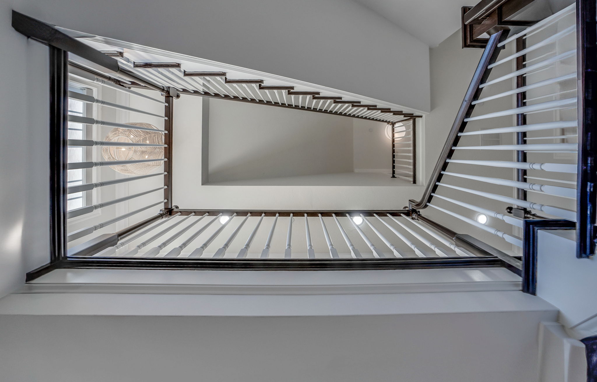 Grand Three-story staircase professionally refinished and stained including handrail, newels, and balusters