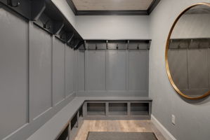 Custom built mudroom with built in benches and coat hangers, and detailed wood ceiling