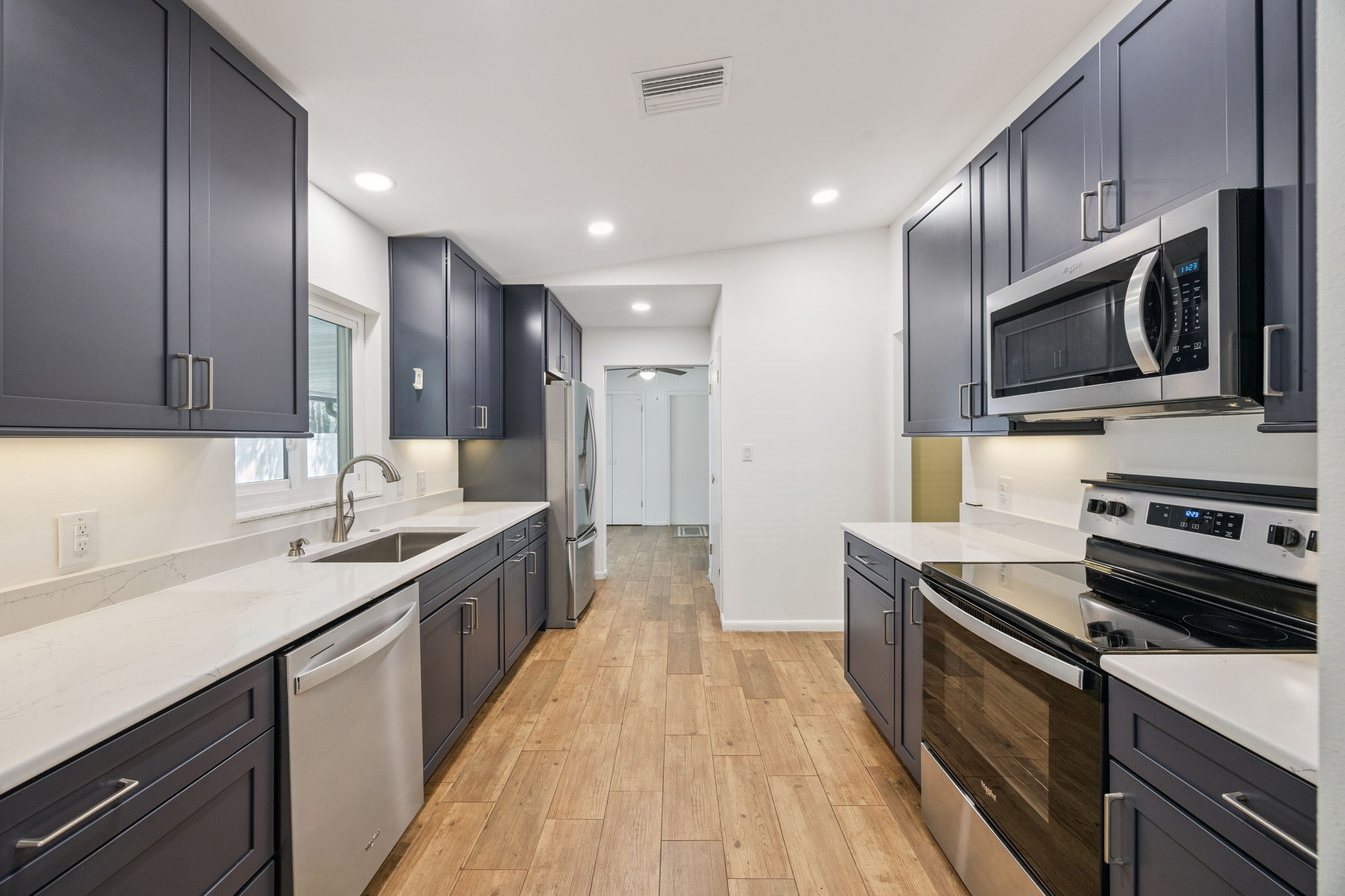 Newly updated kitchen with modern finishes, soft close cabinets, quartz counters, under-cabinet lighting,  and functional layout.
