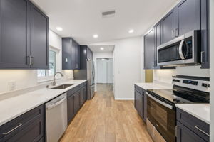 Newly updated kitchen with modern finishes, soft close cabinets, quartz counters, under-cabinet lighting,  and functional layout.