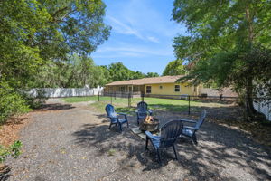 Fully fenced backyard with shade trees and a fire pit area