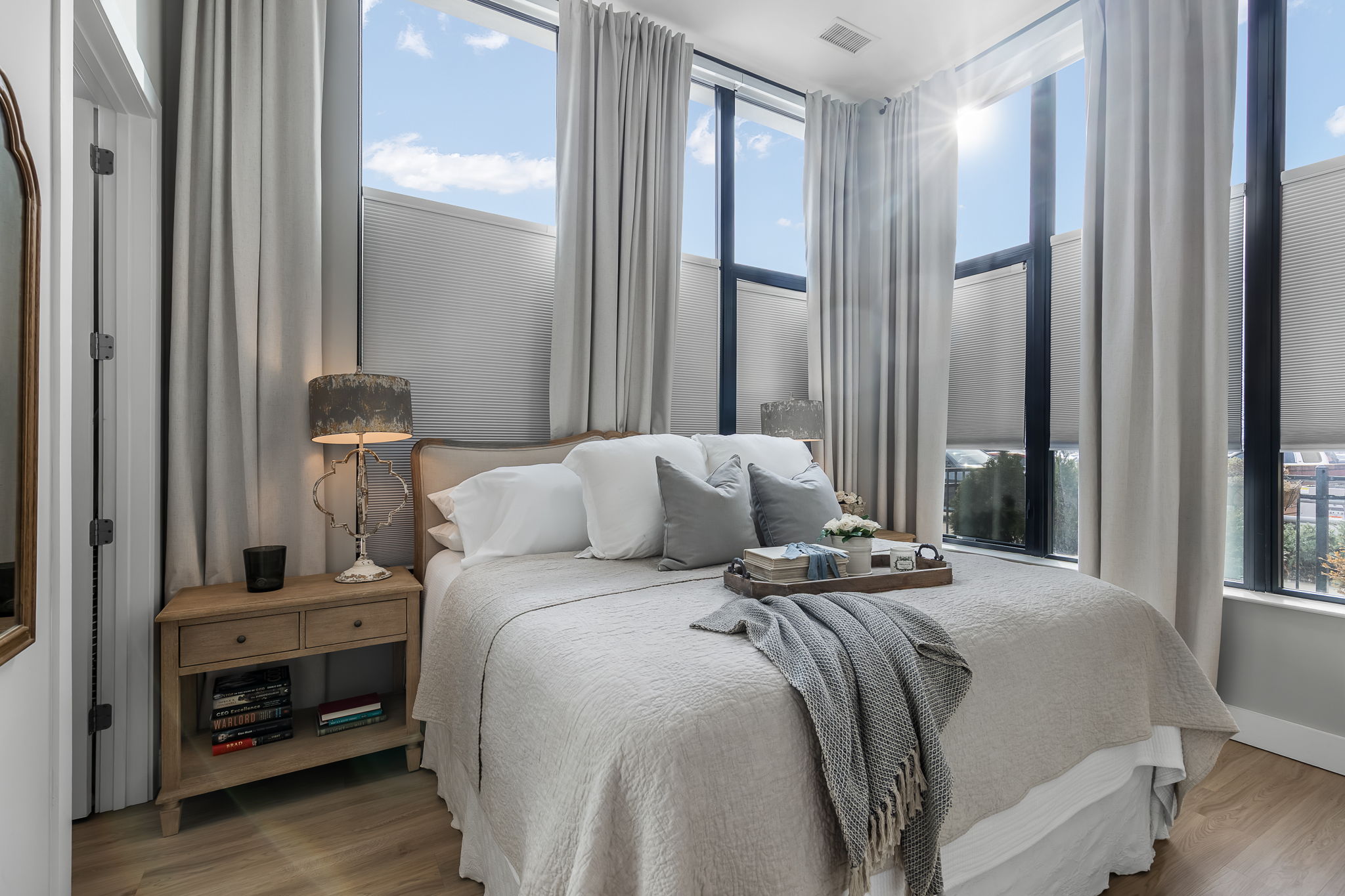 This serene primary retreat boasts abundant natural light from dual exposures, ample space for a king-sized bed, and stylish designer draperies and blinds for a polished finish.