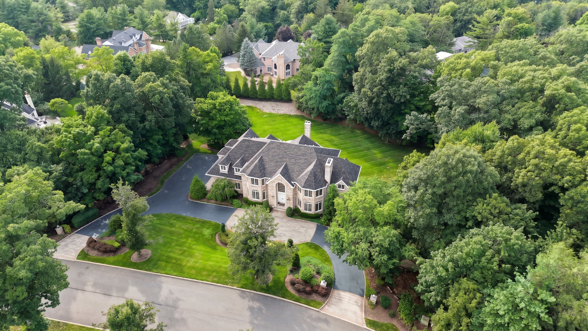 The approach alone tells you what you're in for. A circular driveway, anchored by a paver walkway at its center, sweeps past manicured grounds toward an oversized three-car garage and an entrance built for arrival, framed by brick on three sides of the home's exterior.