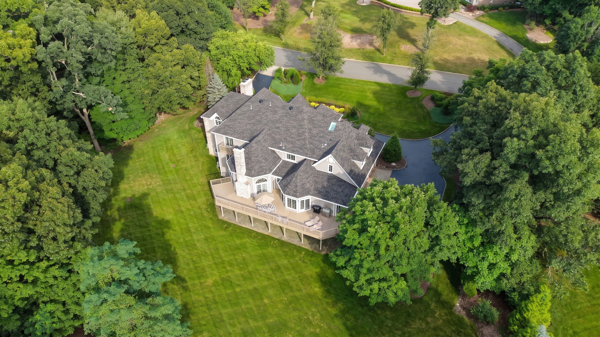 The approach alone tells you what you're in for. A circular driveway, anchored by a paver walkway at its center, sweeps past manicured grounds toward an oversized three-car garage and an entrance built for arrival, framed by brick on three sides of the home's exterior.