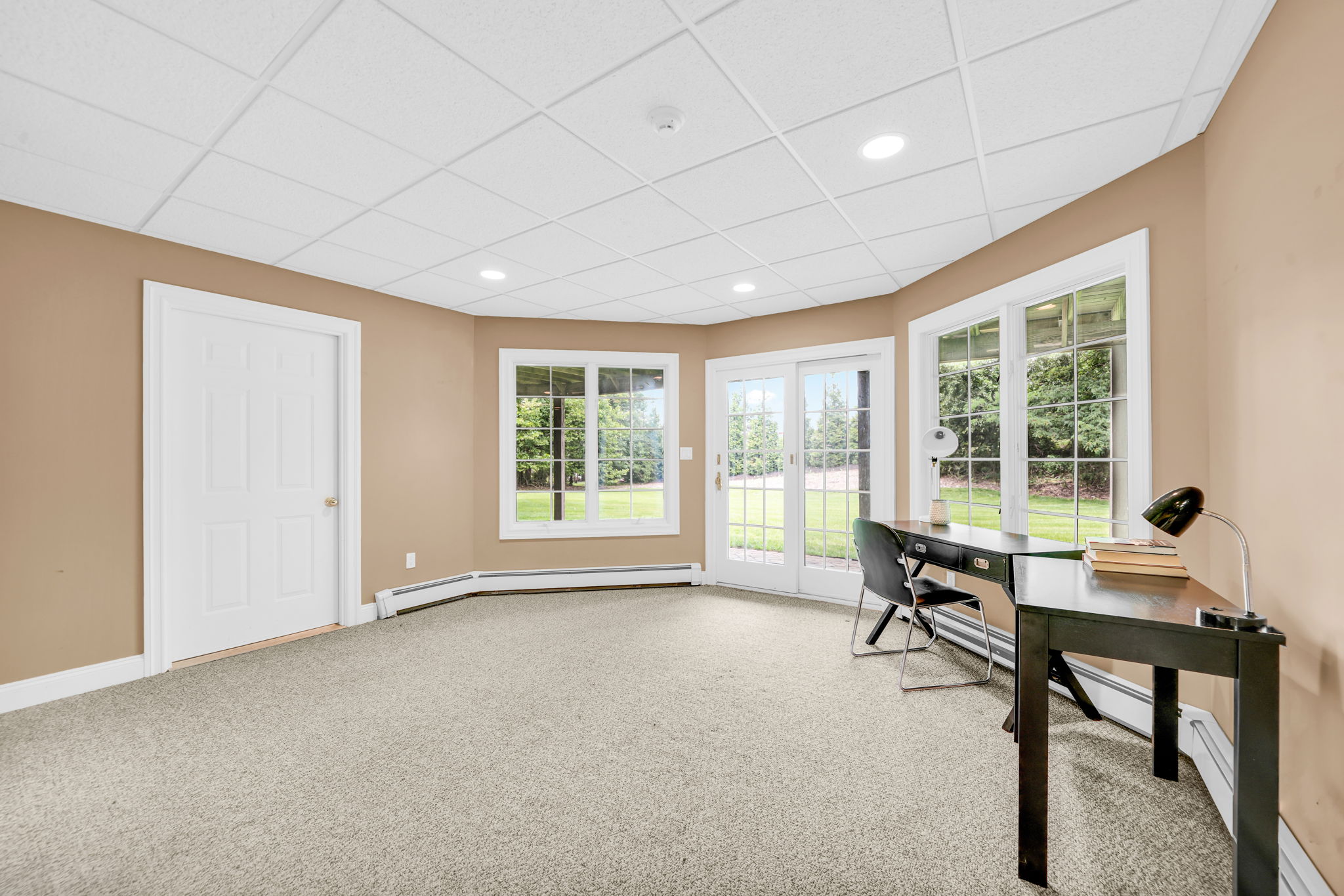 Downstairs, the fully finished and furnished walk-out lower level is built for entertaining, anchored by its own family room warmed by a stone fireplace, oversized windows that flood the space with natural light, French doors leading to a covered patio and the flat, grassy backyard beyond, and its own separate entrance from the garage in addition to access from the main living areas.