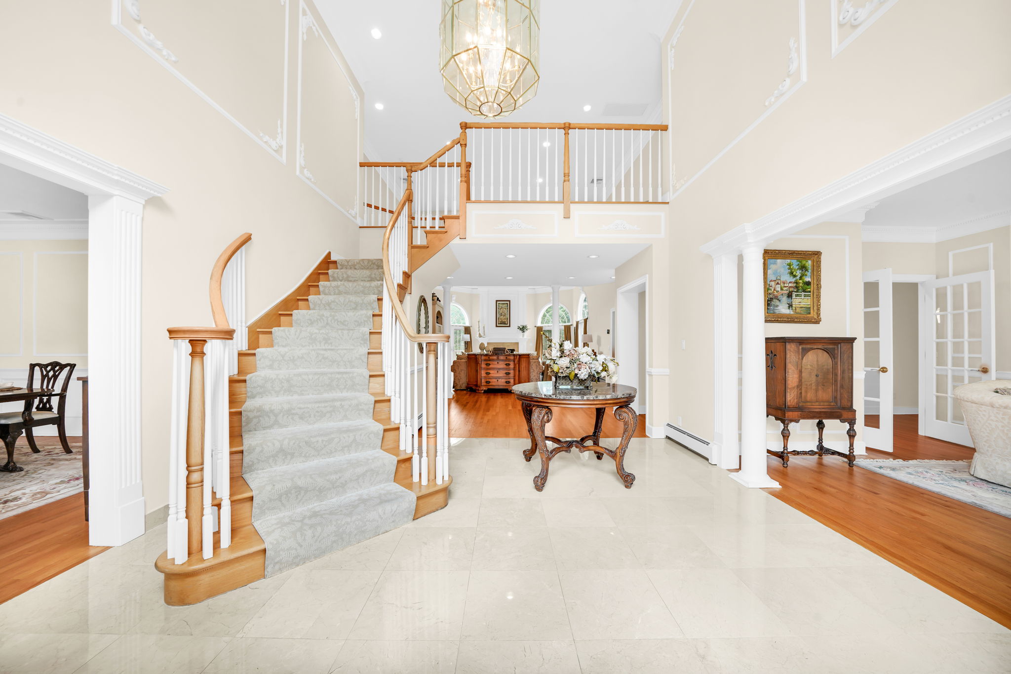 Step through the door into a two-story foyer, where a grand, cascading staircase rises beneath a wall of light