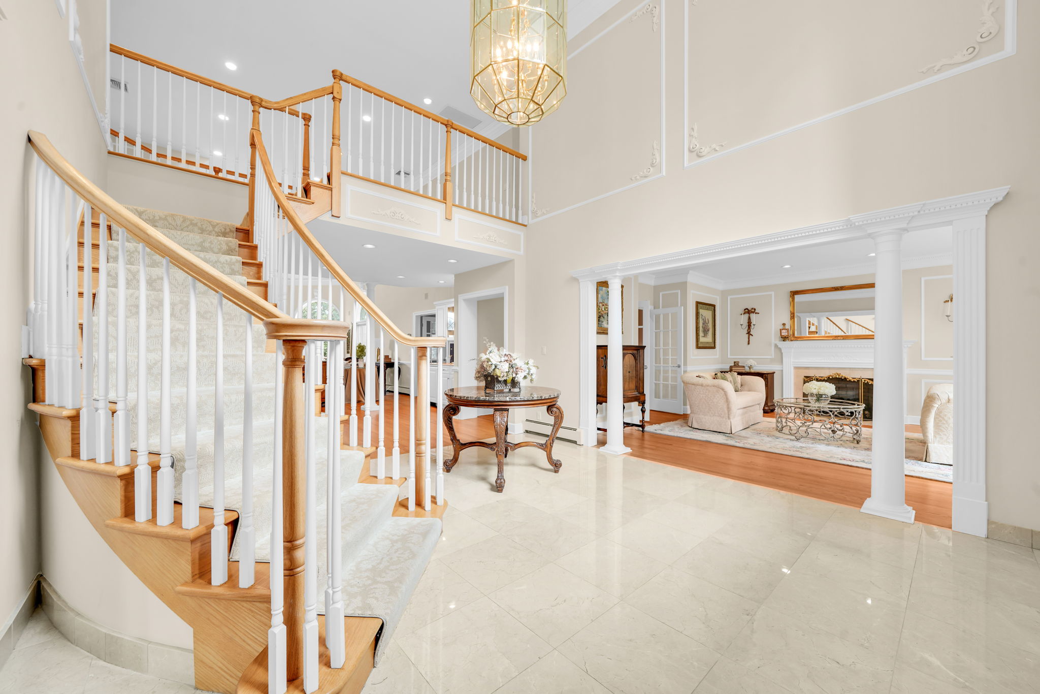 Step through the door into a two-story foyer, where a grand, cascading staircase rises beneath a wall of light