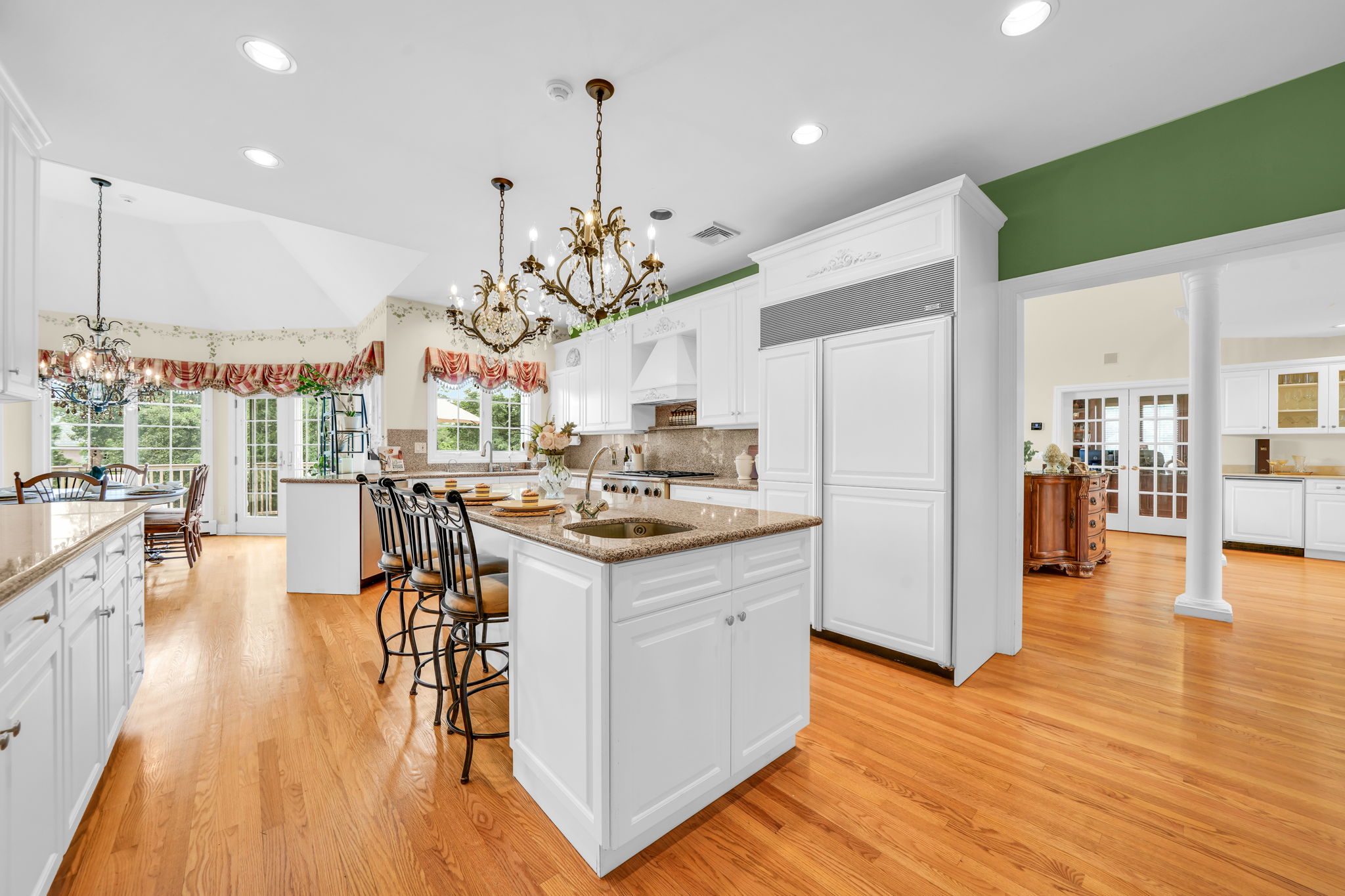 To the left, the kitchen: a bright, all-white showpiece with a large island for prepping or casual dining, an eat-in nook for everyday meals, a walk-in pantry, and a butler's pantry connecting seamlessly to the formal dining room. And just off the kitchen, in a detail only a homeowner who truly lived in the space would think to include, a second staircase with a wooden ladder rail, scaled for little hands and big hands alike, is tucked charmingly beside the everyday comings and goings of family life.