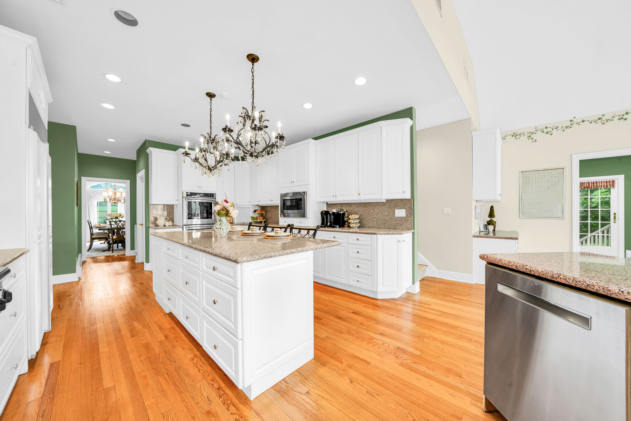 To the left, the kitchen: a bright, all-white showpiece with a large island for prepping or casual dining, an eat-in nook for everyday meals, a walk-in pantry, and a butler's pantry connecting seamlessly to the formal dining room. And just off the kitchen, in a detail only a homeowner who truly lived in the space would think to include, a second staircase with a wooden ladder rail, scaled for little hands and big hands alike, is tucked charmingly beside the everyday comings and goings of family life.